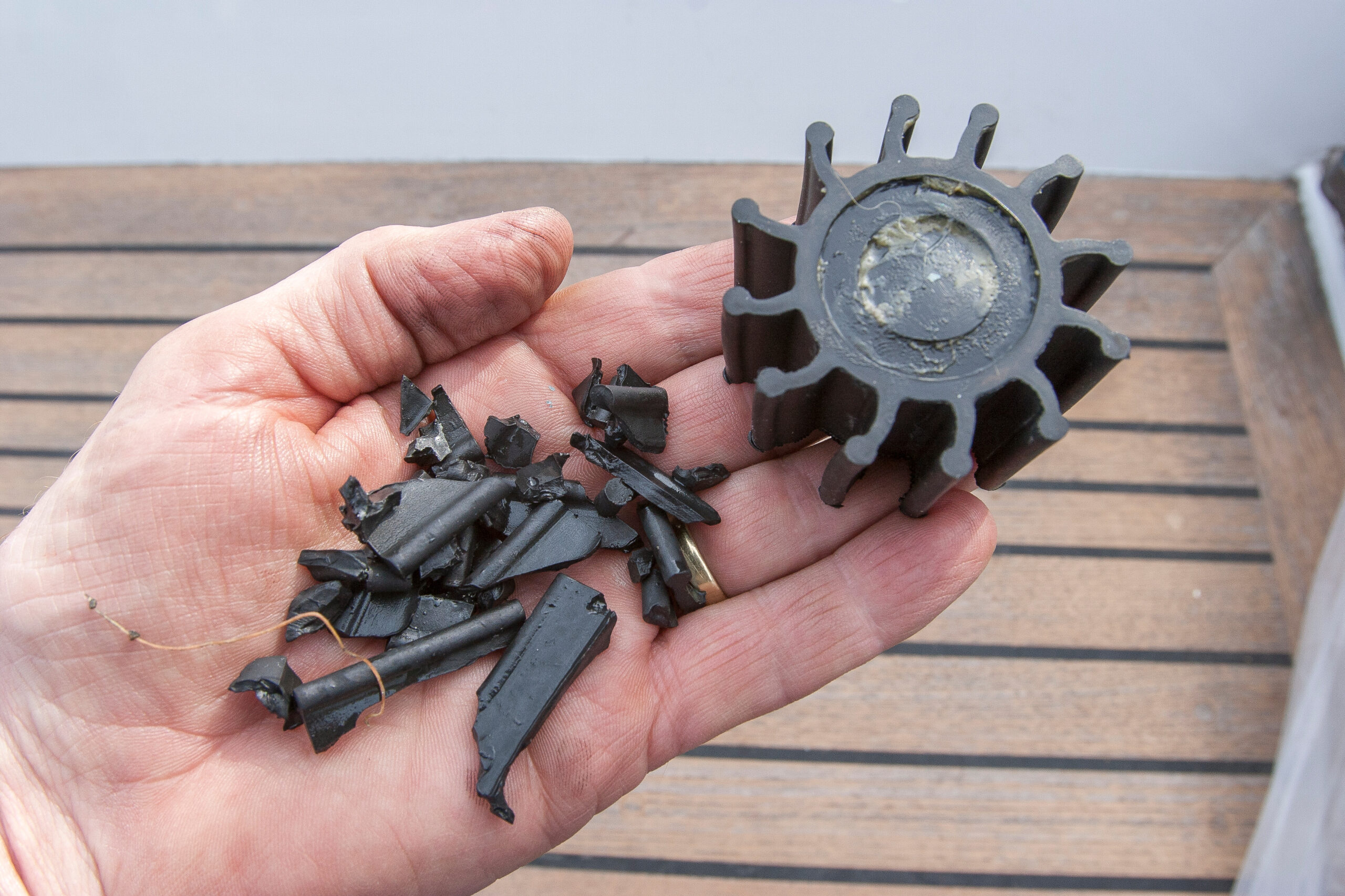 Beschädigter Gummi-Impeller mit abgebrochenen Flügeln und Bruchstücken in einer Hand